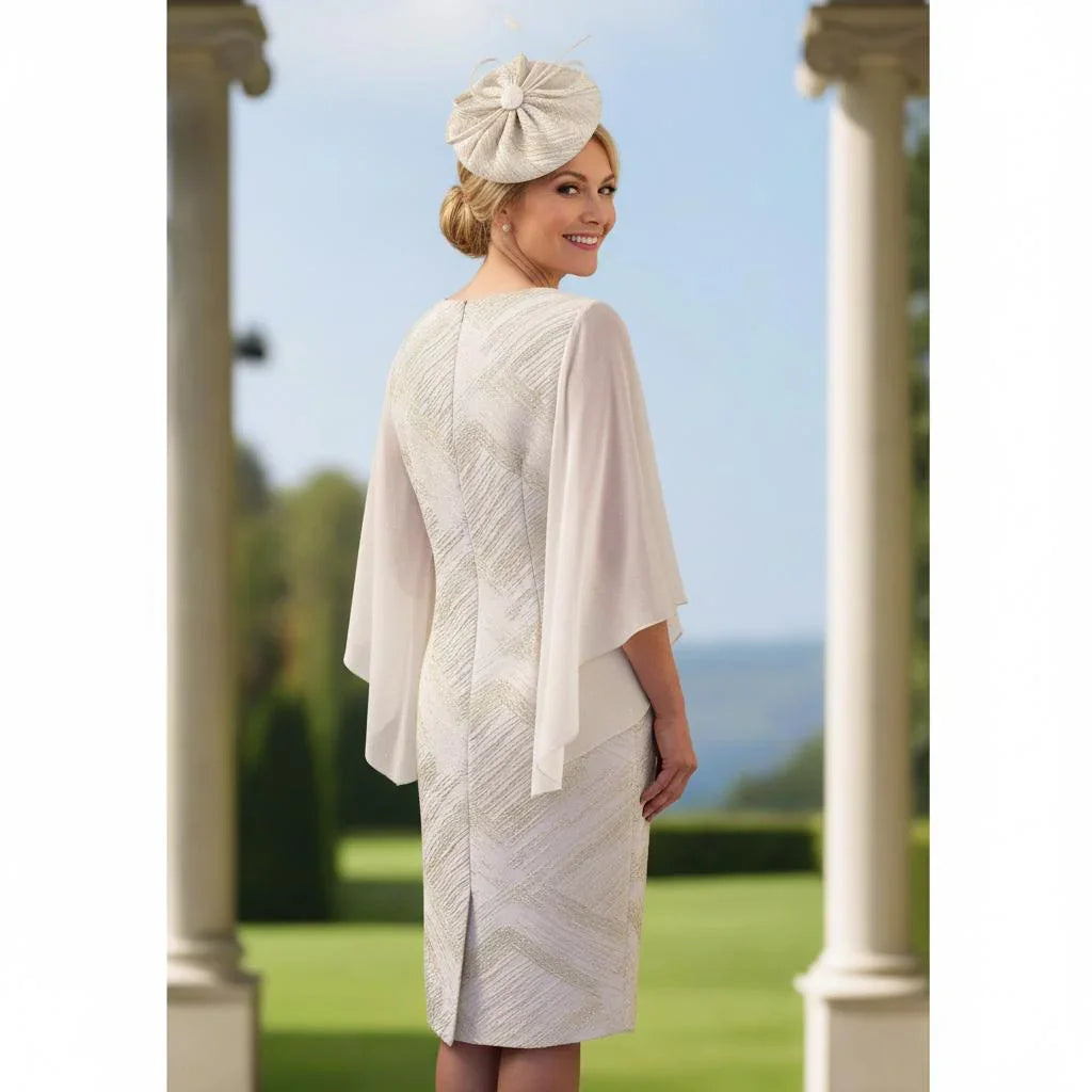 Woman in a Lizabella Champagne mother of the bride dress standing on a balcony with a scenic background. Signature Dress.