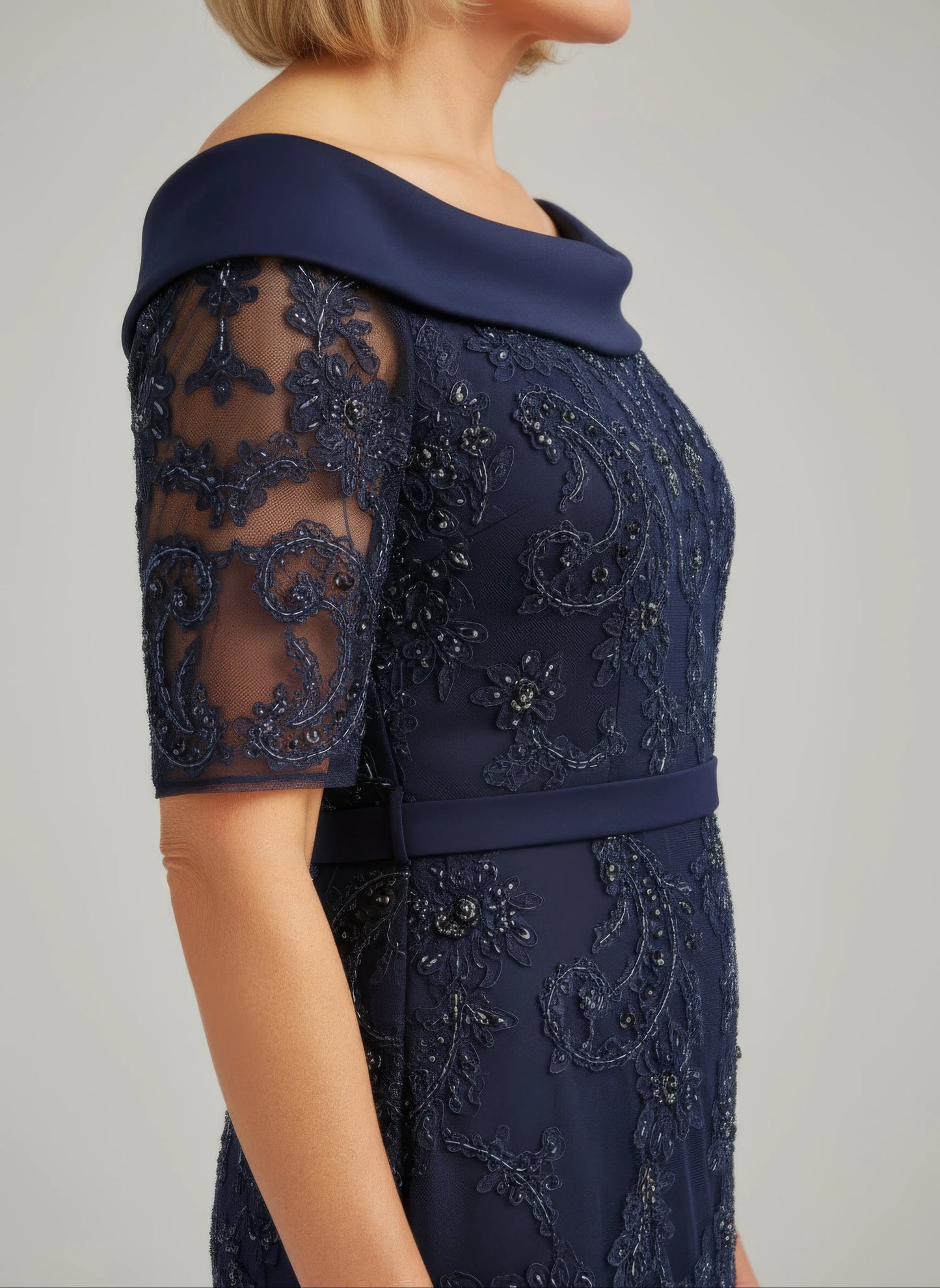 Woman in a navy Veni Infantino dress with lace details standing on a balcony with a scenic background