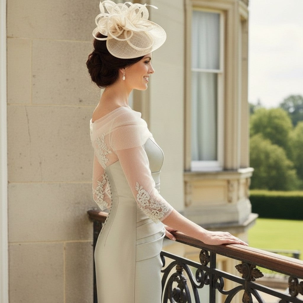 Woman in a elegant gold mother of the bride dress and hat standing on a balcony with a scenic background