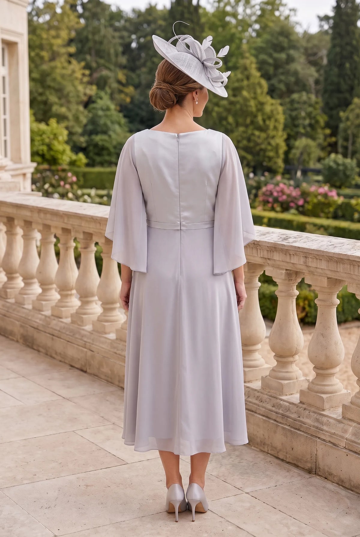 Back view of the silver Lizabella 2344 Mother of the Bride dress showing its elegant shape and matching silver fascinator.