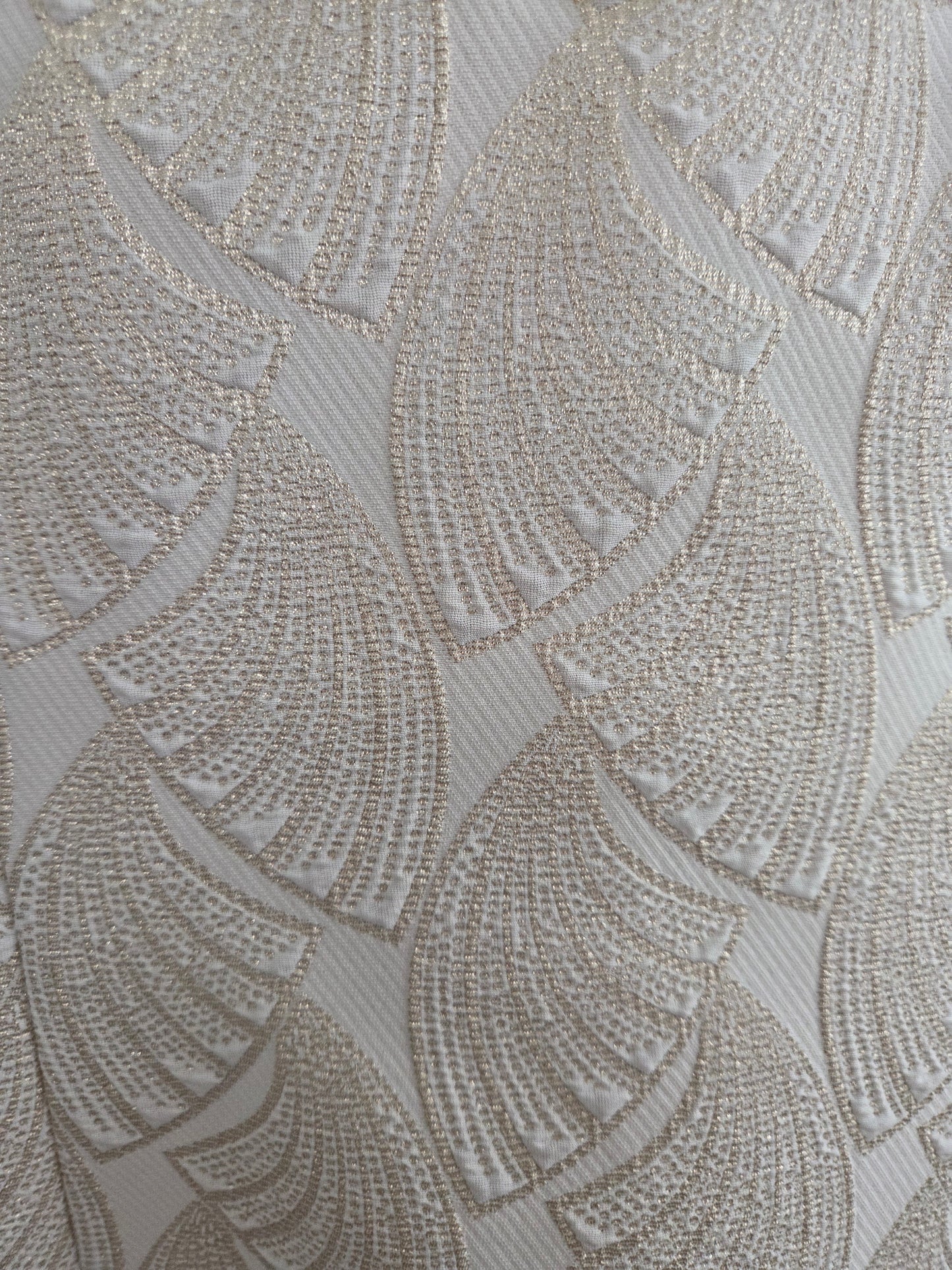 Textured fabric with a pattern of raised circular shapes in gold and beige tones.