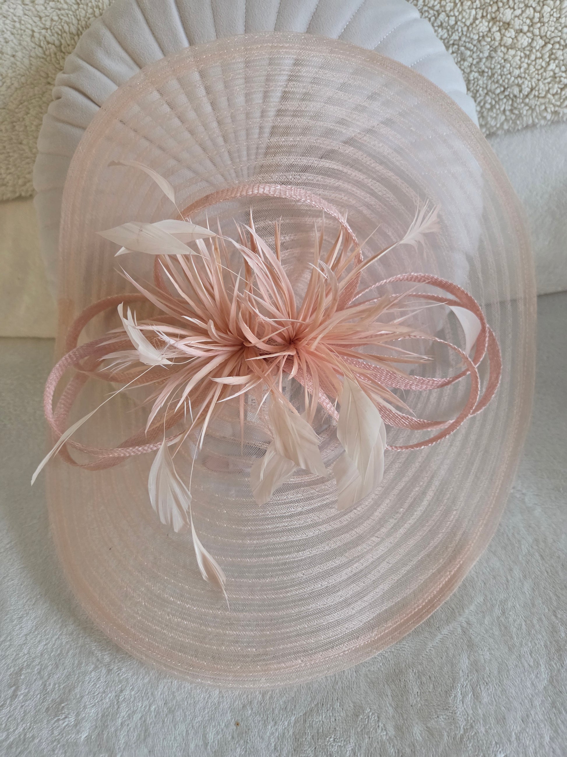 Pink decorative hat with feather details on a light background