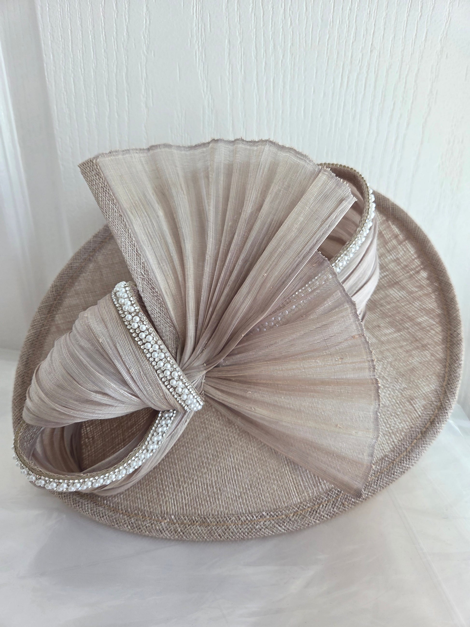 Beige fascinator with tulle and embellishments on a white background