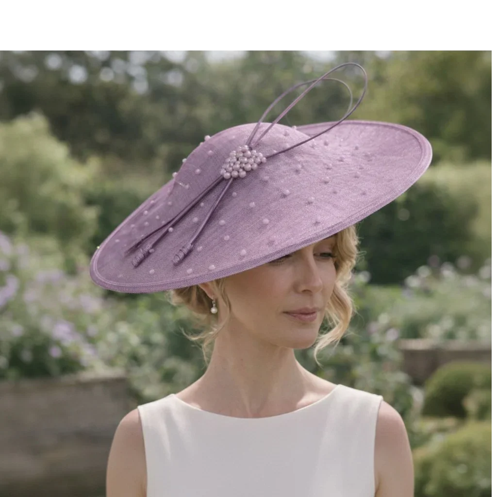 Woman wearing a Jbees lilac fascinator hat with a blurred garden