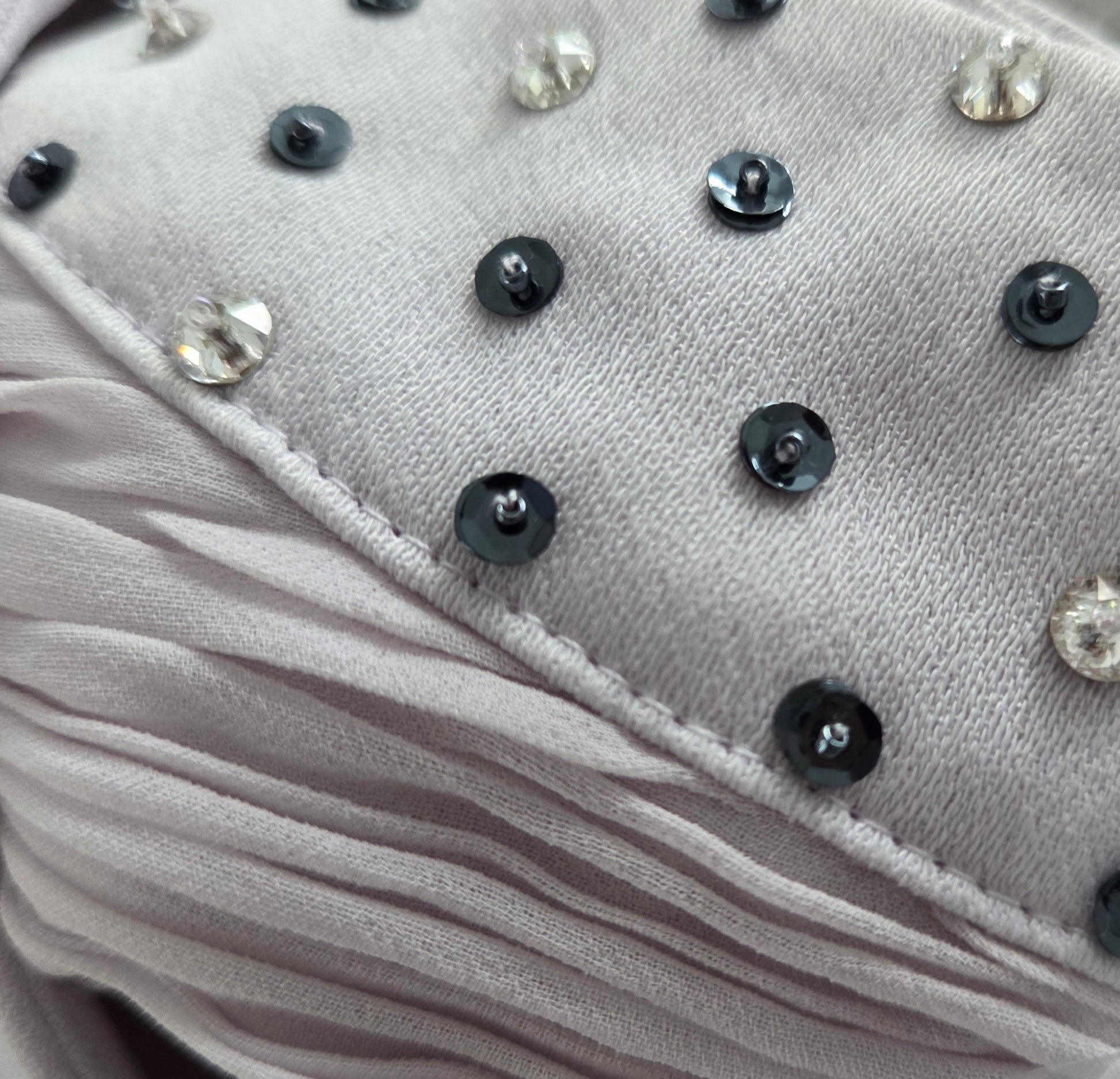 Close-up of a gray fabric surface with black buttons and clear gemstones.