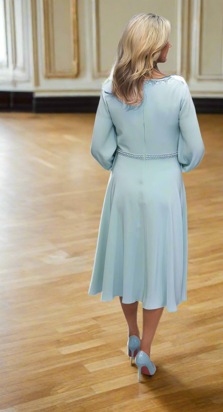 Woman wearing a light blue dress with long sleeves on a white background