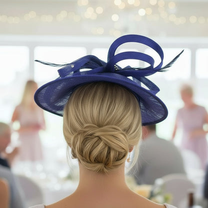 Woman wearing a cobalt blue embellished fascinator hat with feathers in an indoor setting