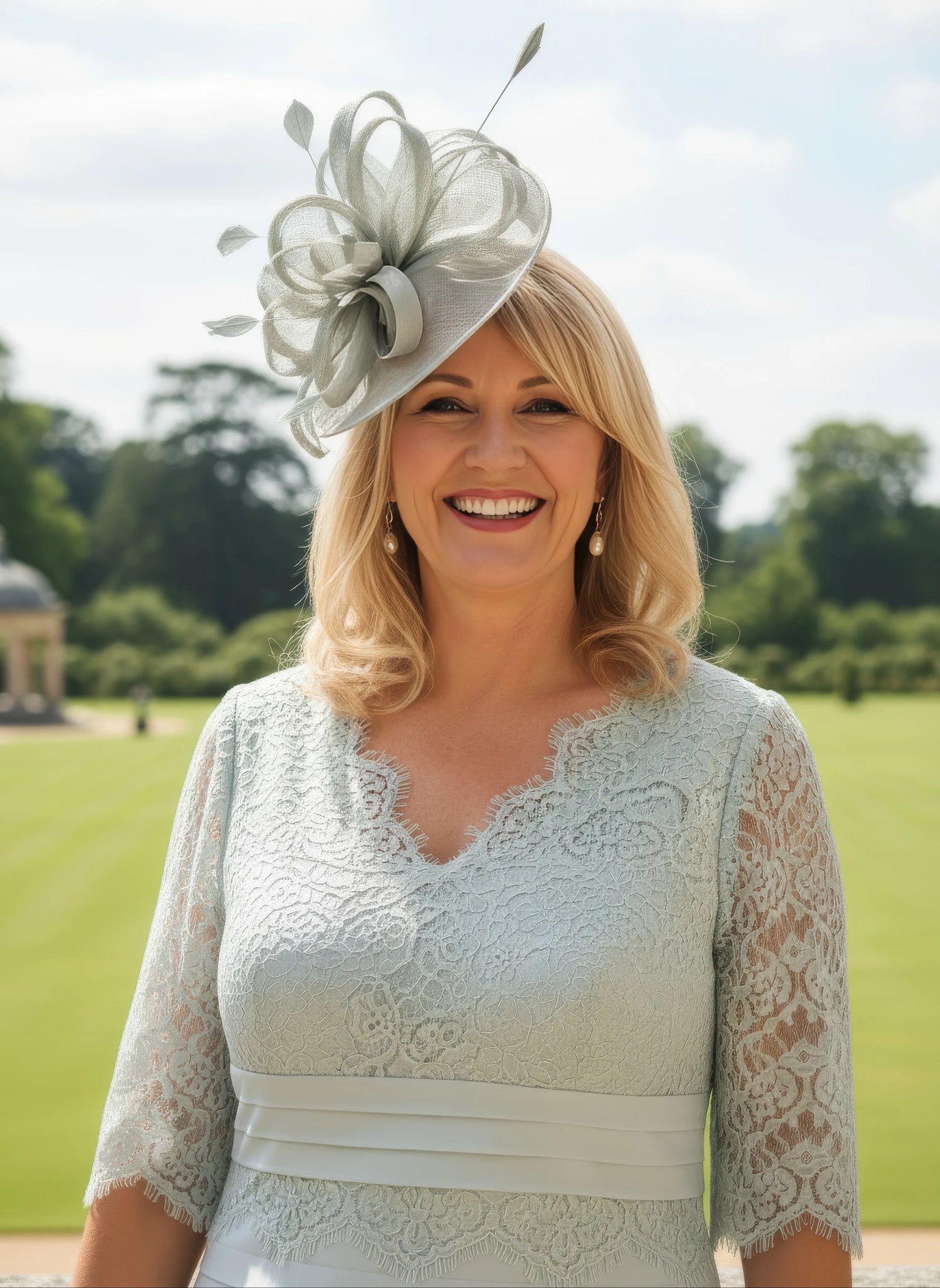 Woman in a light-coloured green condici lace dress and hat standing in a formal garden setting