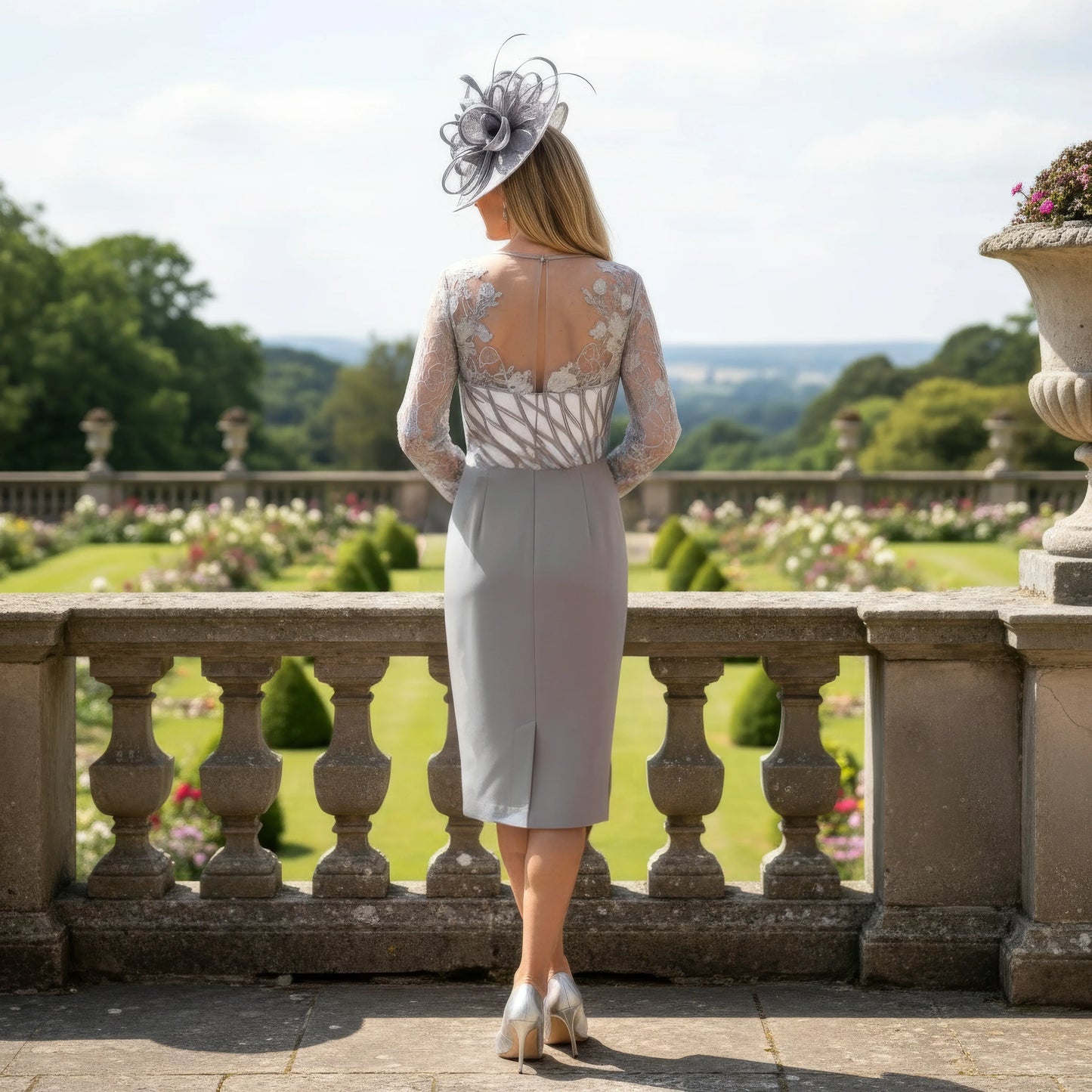 Woman in a stylish Silver grey mother of the bride dress and hat standing on a balcony with a scenic 