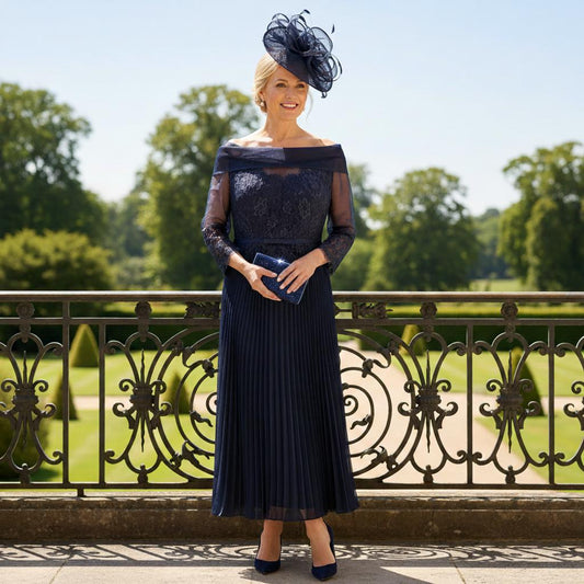 Woman in a Gill Harvey navy mother of the bride dress with a matching navy fascinator hat standing in a garden setting. Signature Dress.