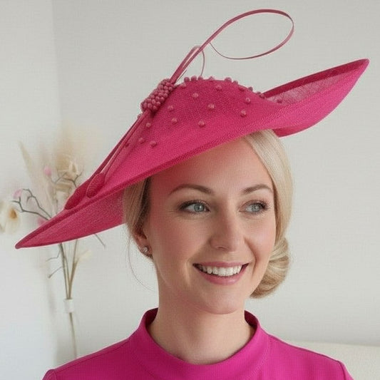 Woman wearing a JBEES Millinery bright cerise pink fascinator wedding hat with a white background
