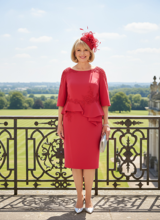Woman in a red dress with a matching hat standing on a balcony with a scenic background
