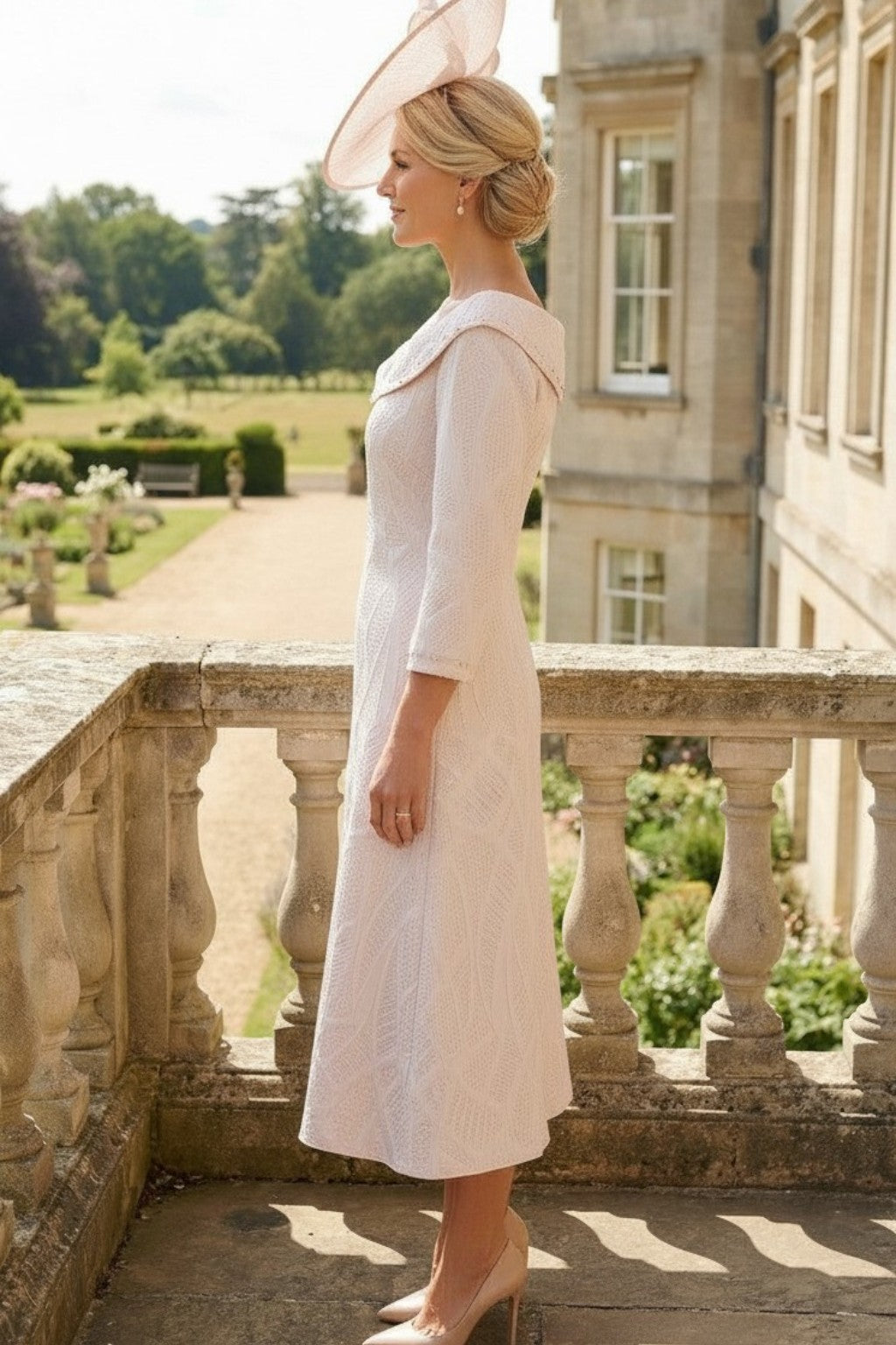 Side view of a woman wearing a lizabella light pink mother of the bride dress dress in an outdoor setting