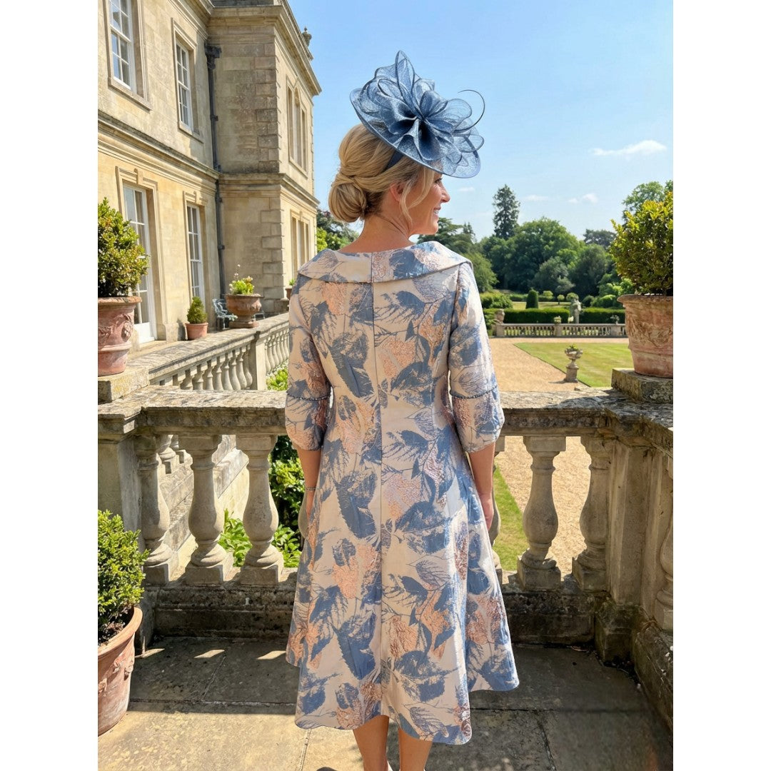 Back view of the Lizabella 2515 blue and gold brocade mother of the bride dress, showing the structured fit, metallic pattern and long sleeves