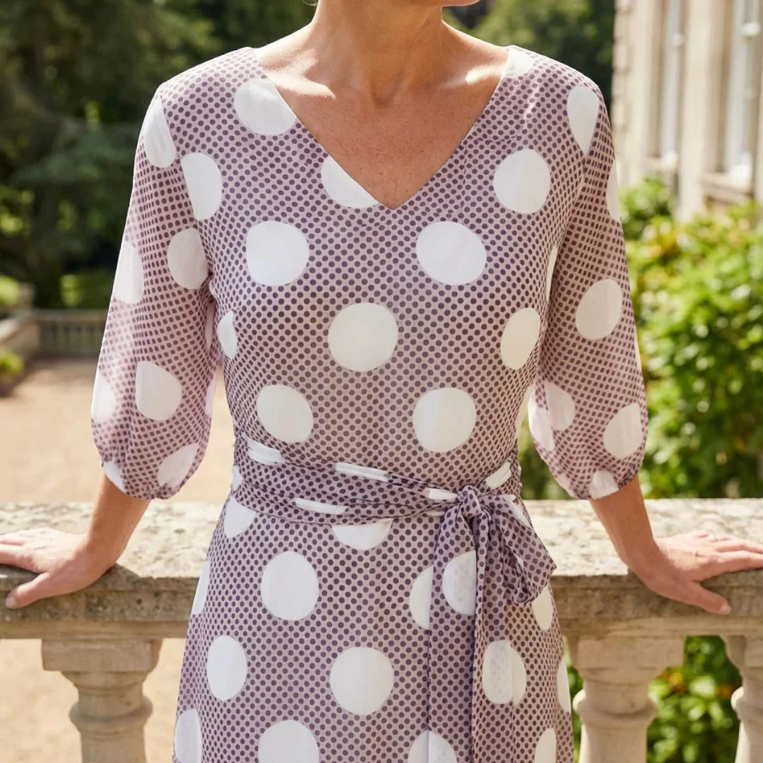 Woman in a Lizabella polka dot taupe mother of the bride dress and taupe fascinator