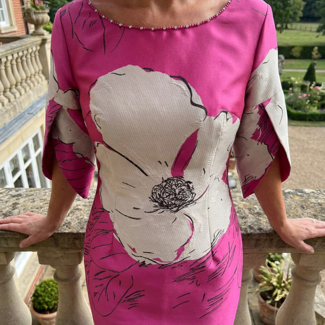 Close‑up of the Lizabella 2945 fuchsia pink mother of the bride dress showing the pink pearls and rhinestones along the neckline