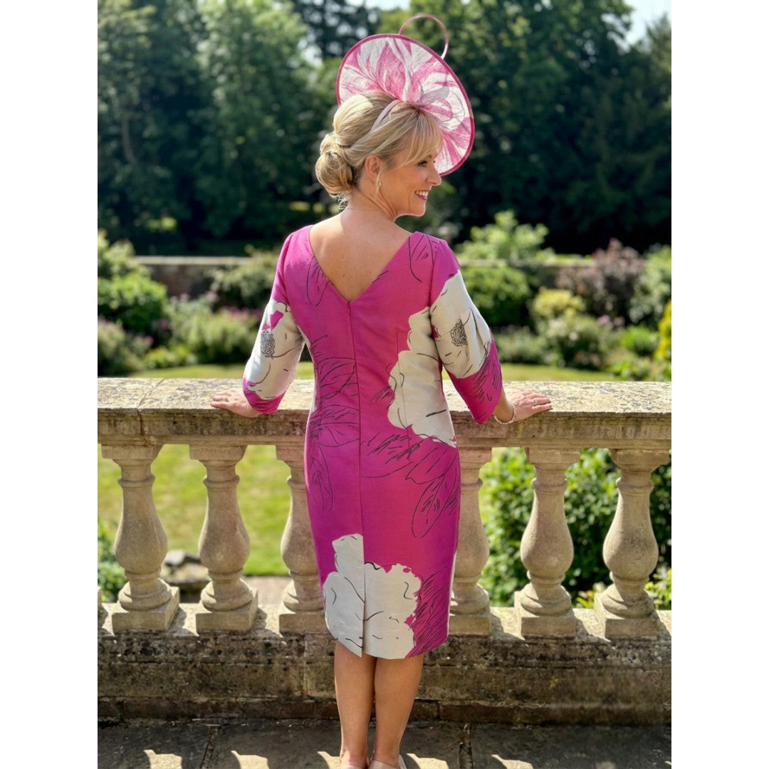 Back view of the Lizabella 2945 fuchsia pink mother of the bride dress with matching pink fascinator and soft flowing skirt.