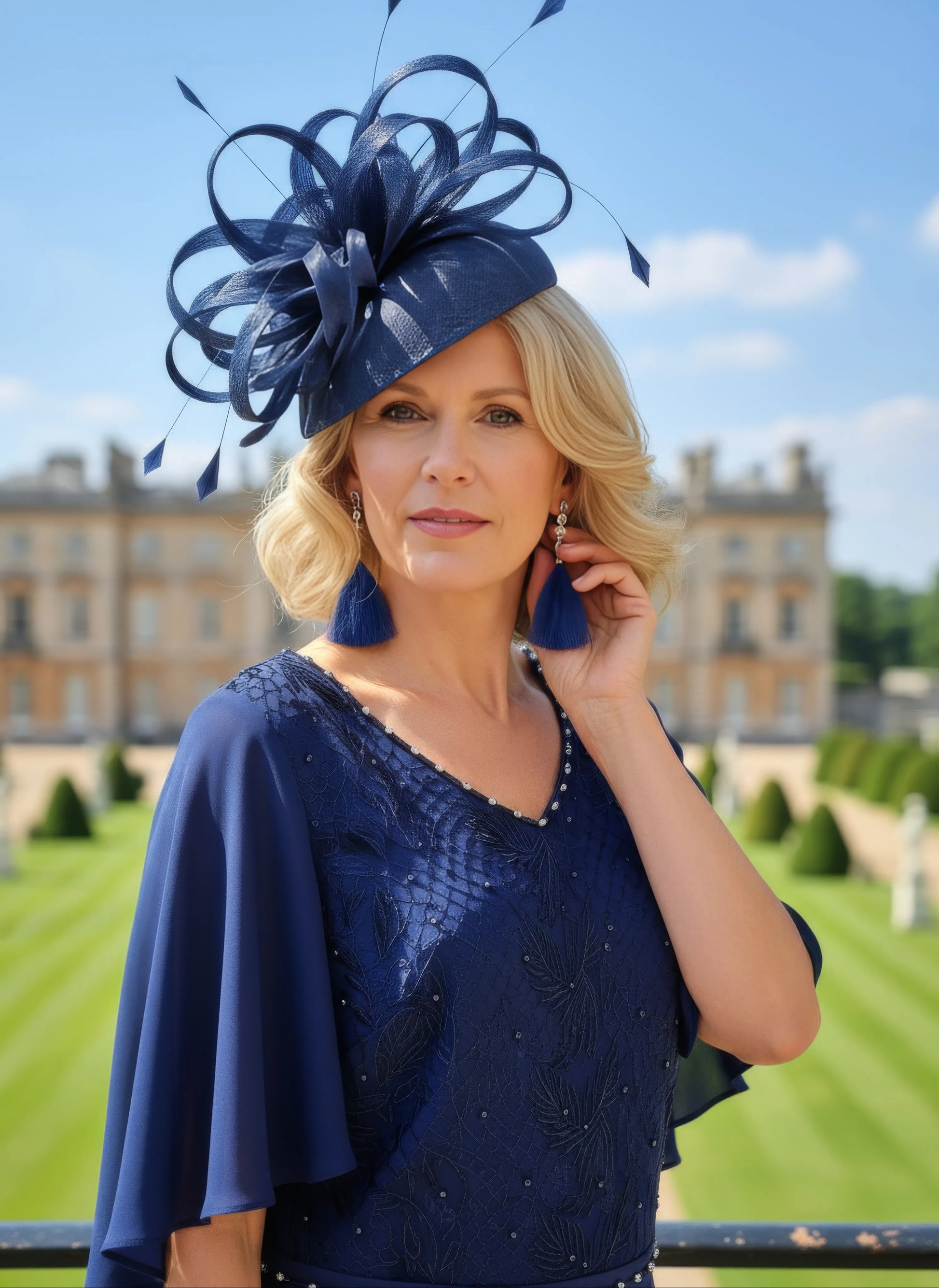 Woman in a cobalt blue dress and hat standing in front of a formal garden wedding setting. Lizabella 2344 - Signature Dress