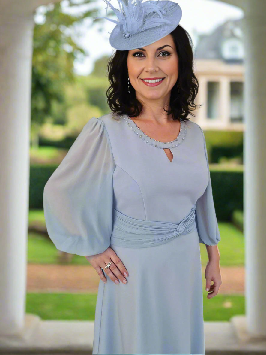 This stylish dress by Lizabella with a round neckline with inset v and bead detail has a voile 3/4 sleeve and pleat detail to waistline. The A Line style skirt completes the very flattering style.