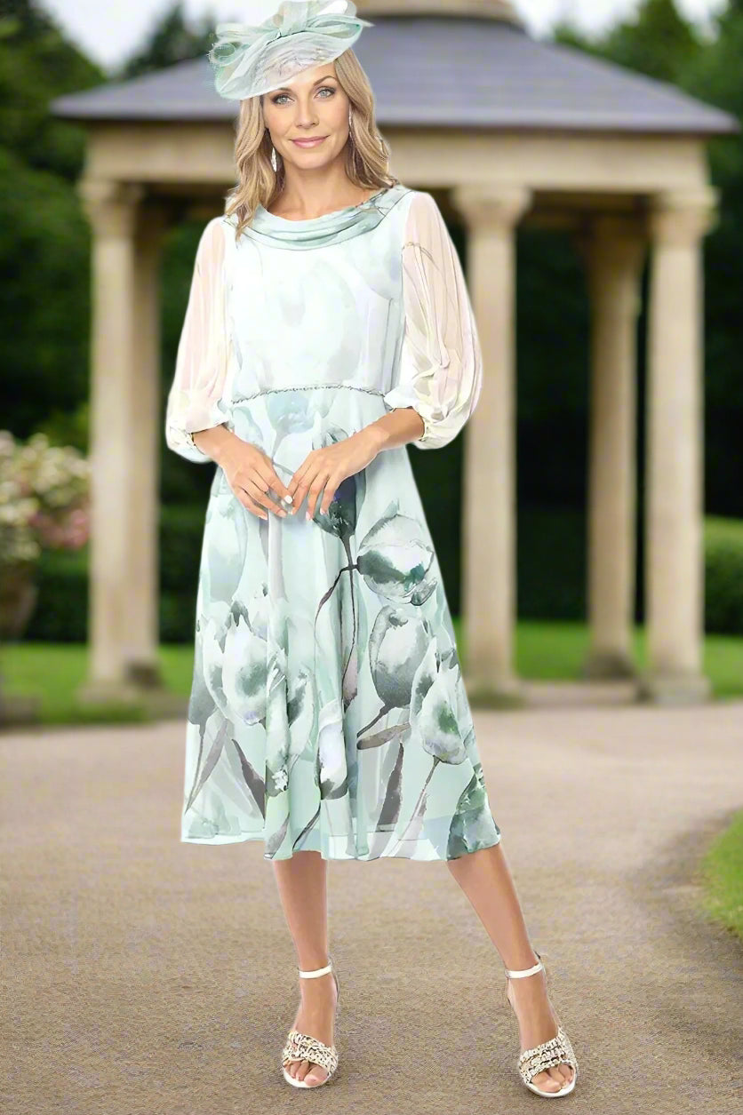 Lizabella dress in ice green and ivory floral chiffon fabric. Features draped neckline, 3/4 sleeves, and full skirt. Waist adorned with diamante detail.