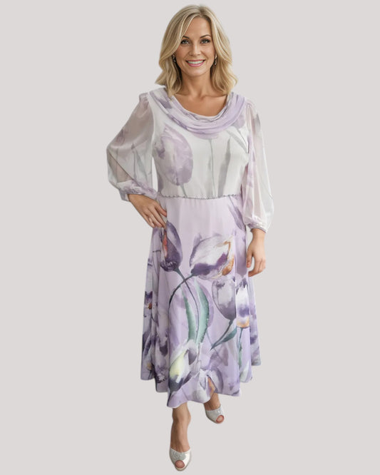 A beautiful dress in purple floral chiffon fabric.  The A line dress has a draped neckline with full 3/4 sleeves. a perfect dress for the mother of the bride.