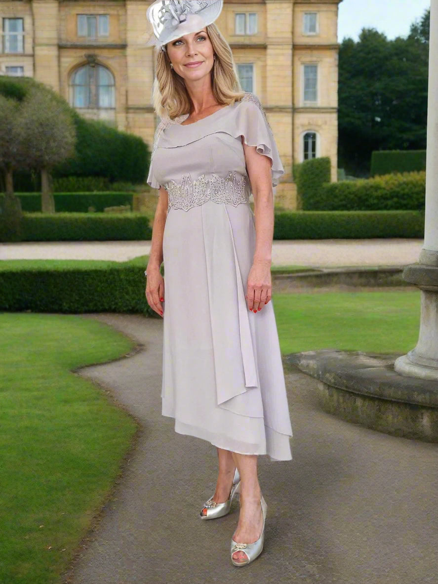 Mother Of The Bride beautiful chiffon dress by Lizabella, is a fit with slight flare and a attached cape looking sleeve, concealed zip to the back and lined, finished with embellished beads to the centre front.