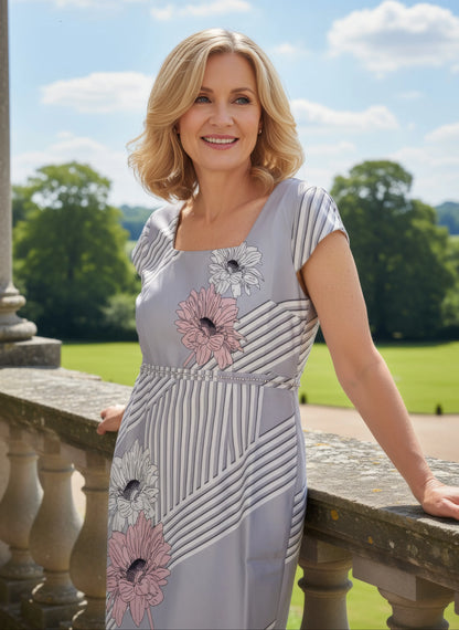 Woman in formal 2 piece dress and jacket from Lizabella standing on a balcony with a garden background attending a wedding as mother of the bride - Signature Dress.