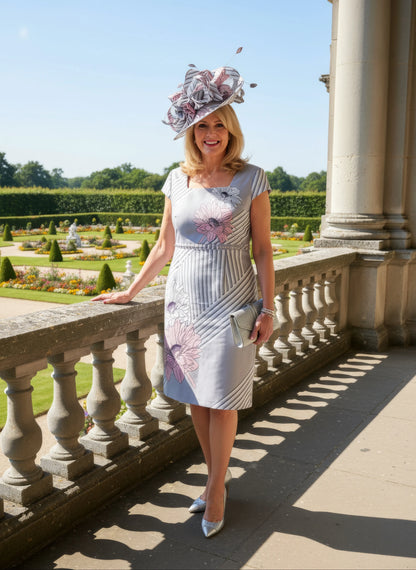 Woman in formal 2 piece dress and jacket from Lizabella standing on a balcony with a garden background attending a wedding as mother of the bride - Signature Dress.