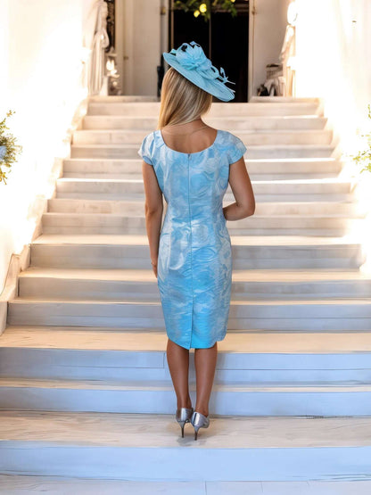 The Michaela Louisa dress features a vibrant blue and silver shimmer color, with cap sleeves, a v-neck, and a floral print. Meticulously designed with a discreet zip closure and full lining for a flawless finish