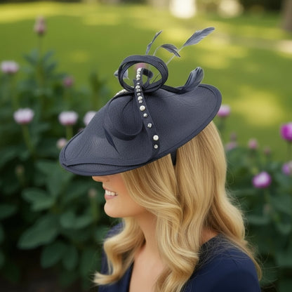Woman wearing a dark blue decorative hat with feathers against a blurred garden background