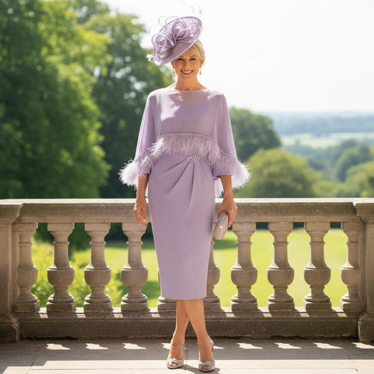 Woman in a lavender veni infantino 2 piece outfit with a matching fascinator hat standing on a balcony with greenery in the background. Signature Dress
