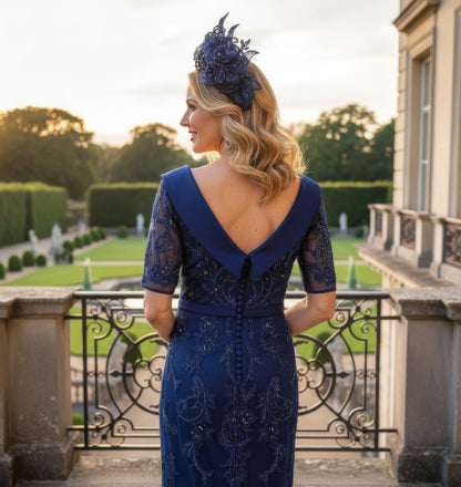 Woman in a navy Veni Infantino dress with lace details standing on a balcony with a scenic background