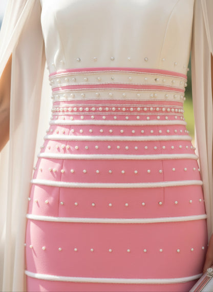 Woman in a pink veni infantino dress with a white cape standing on a balcony with a scenic background