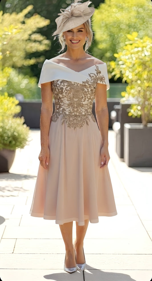 Woman in a beige and white dress with floral embellishments standing outdoors.