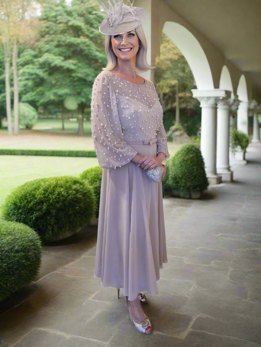 Veni Infantino dress featuring pearl-embellished semi-sheer bodice, wide sleeves, and a flowing midi skirt. A thin waistband accentuates the waistline.