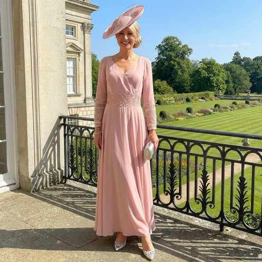 Woman in a veni infantino long pink mother of the bride dress standing on a balcony with a garden and building in the background. Signature Dress.