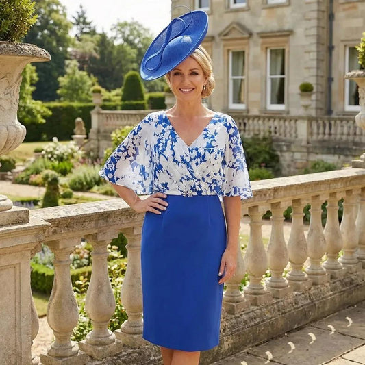 Full outfit view of the Veromia VO9179 cobalt blue floral print dress with cape sleeves and fitted skirt, photographed in front of a grand stone building