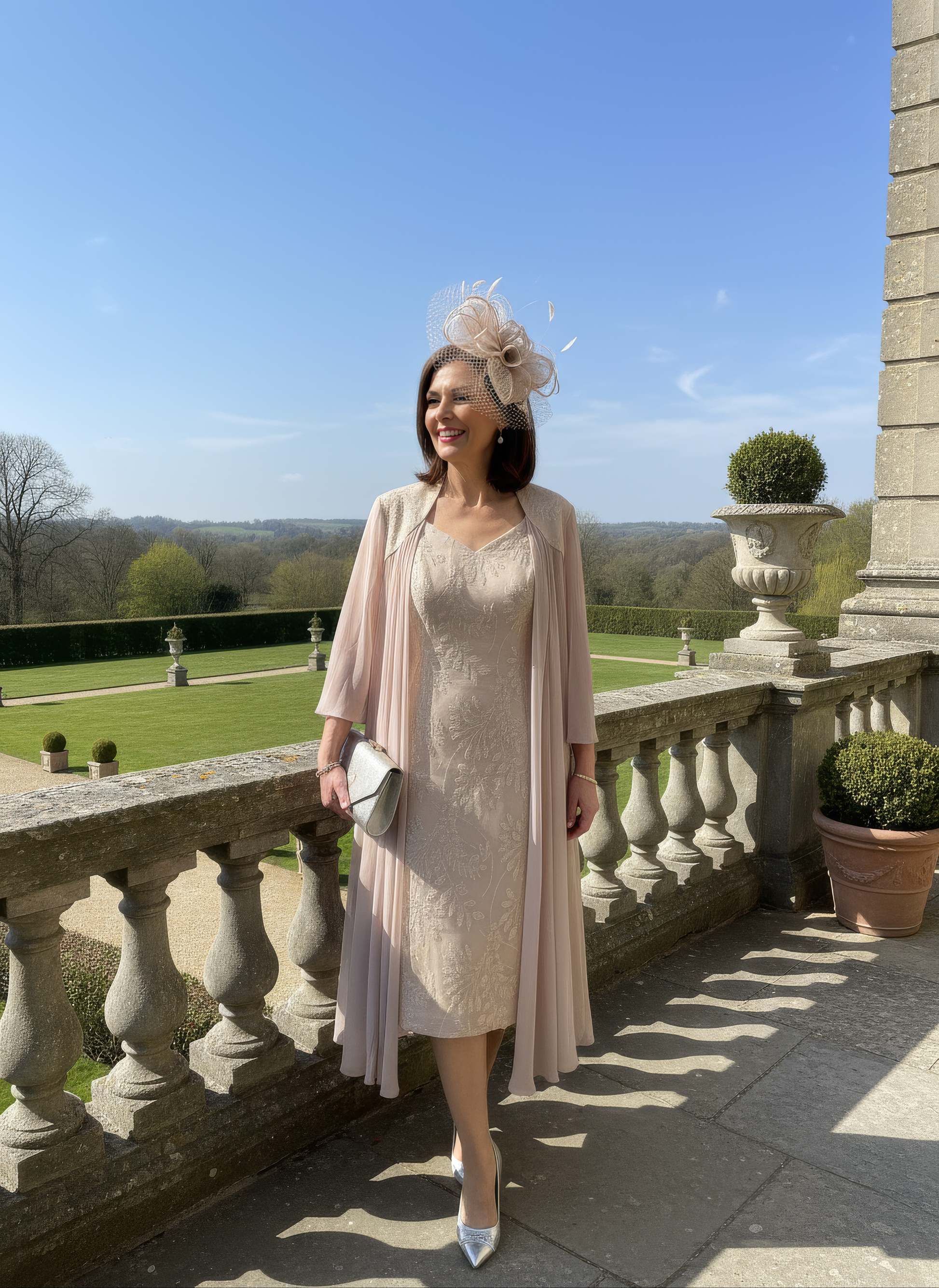 Woman in a light dress and cardigan standing on a balcony with a scenic background