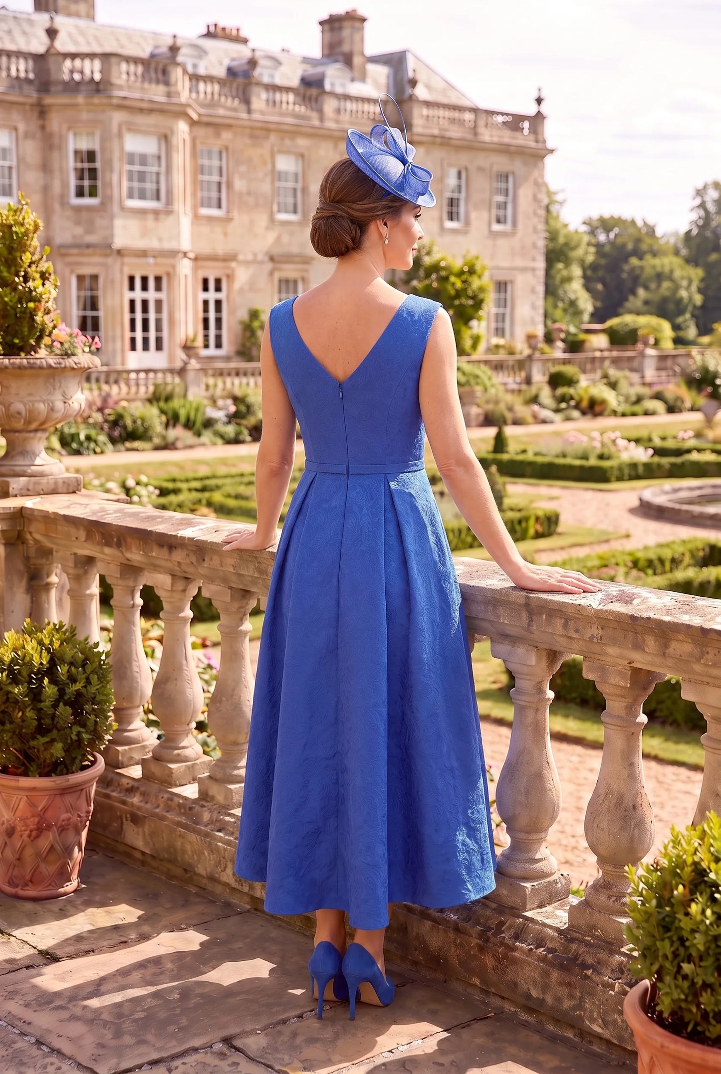 Rear view of the Blue Mother of the Bride Outfit by Rosa Clará Couture Club 3G2B0 showing the flowing high-low hem and coordinating jacket.