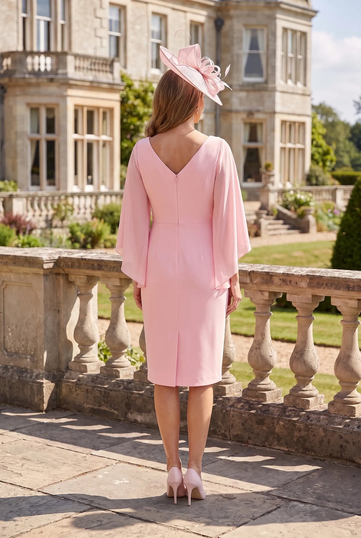 Back view of the blush pink Lizabella 2041 Mother of the Bride dress showing its V-shaped back and flowing sleeves.