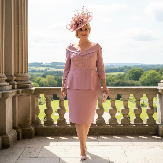 Woman in a curvy pink mother of the bride dress by Veromia standing on a balcony with a scenic view