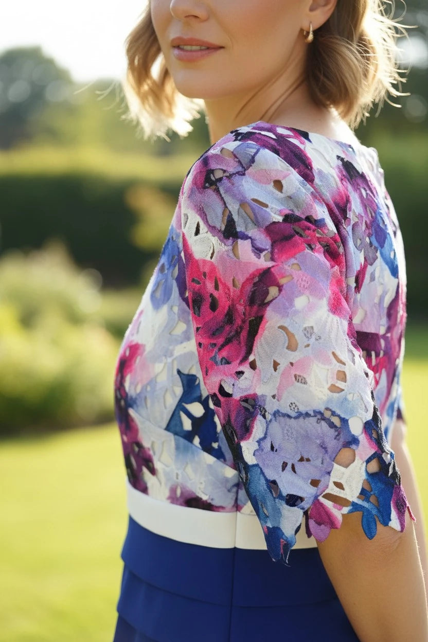 Woman wearing a colorful floral  cobalt blue mother of the bride dress with a blurred green outdoor background