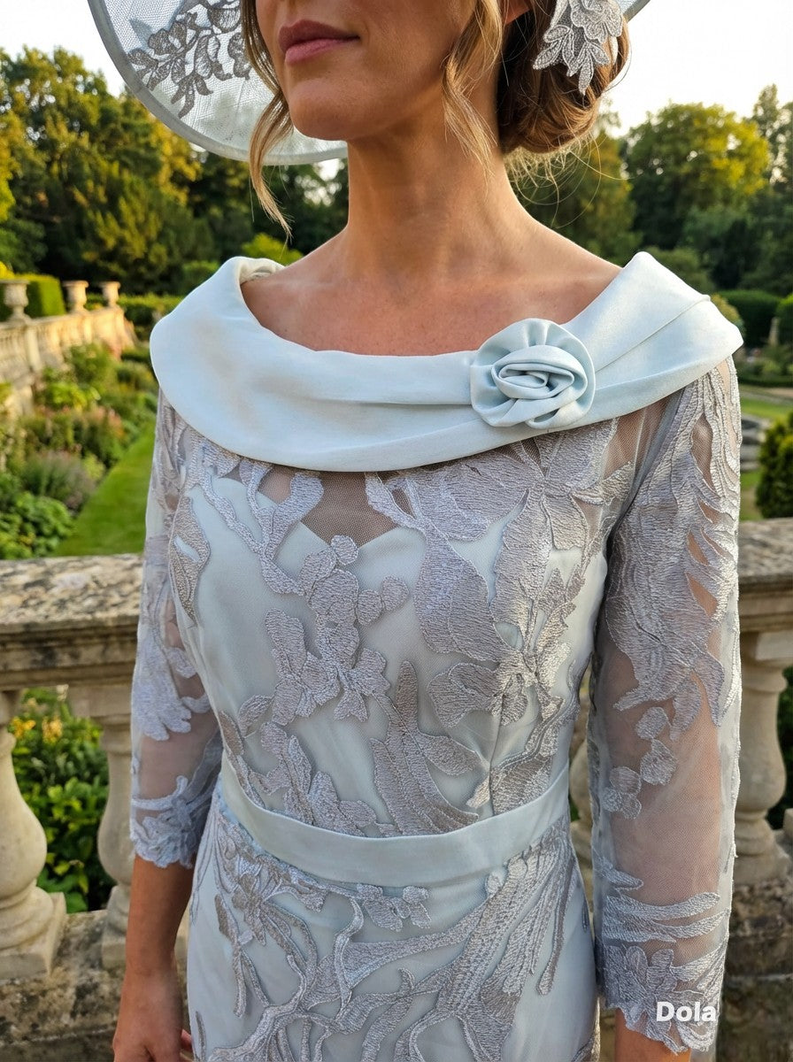 Mint green Couture Club 4G171 mother of the bride outfit with lace detailing and matching hat on a stone terrace.