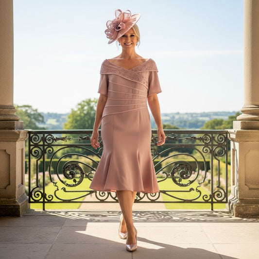 Woman in a irresistible veromia pink mother of the bride dress standing on a balcony with a scenic view