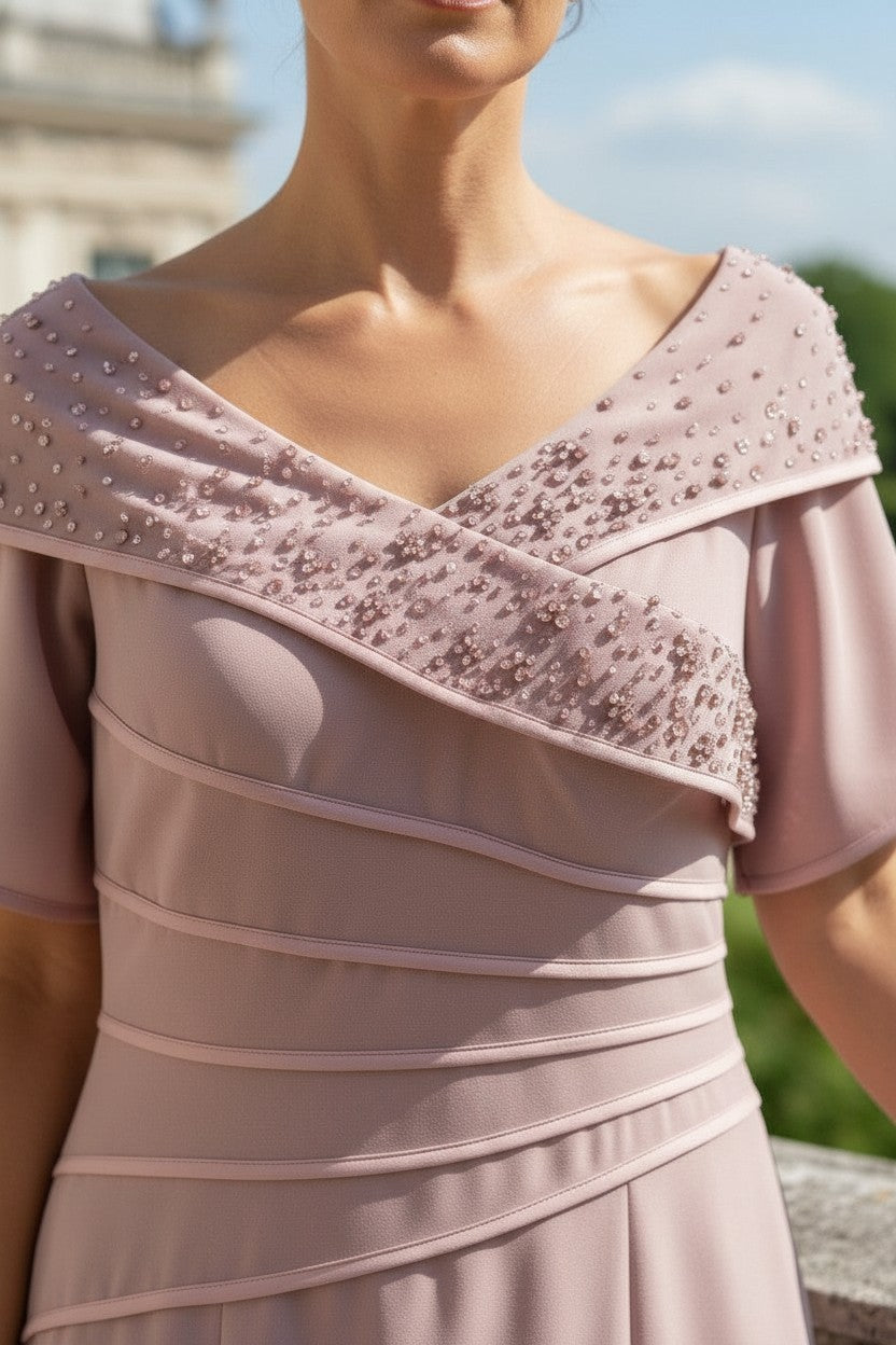Pink off-shoulder irresistible veromia pink mother of the bride dress with intricate detailing on a blurred outdoor background