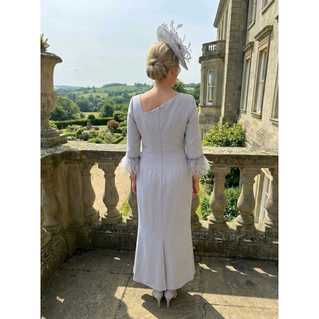 Back view of the Fely Campo 23053 silver dress with feather cuffs, shown in an elegant garden setting.