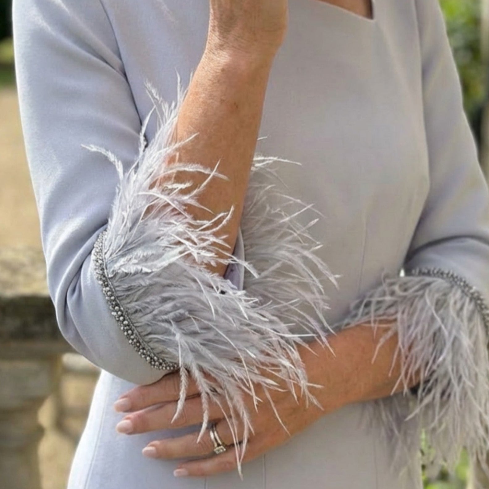 Close‑up of the Fely Campo 23053 silver dress showing soft stretch fabric and feather cuff detail