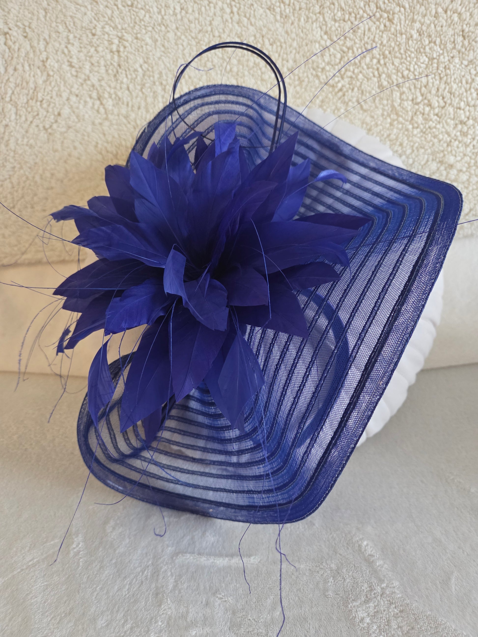 Large Cobalt Blue feathered fascinator headpiece on a textured surface