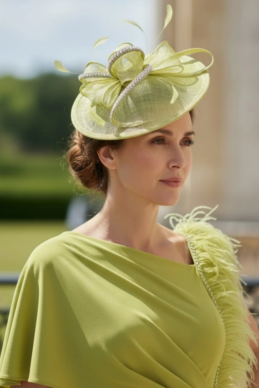 Woman wearing a lime green dress and matching fascinator hat with feathers outdoors.