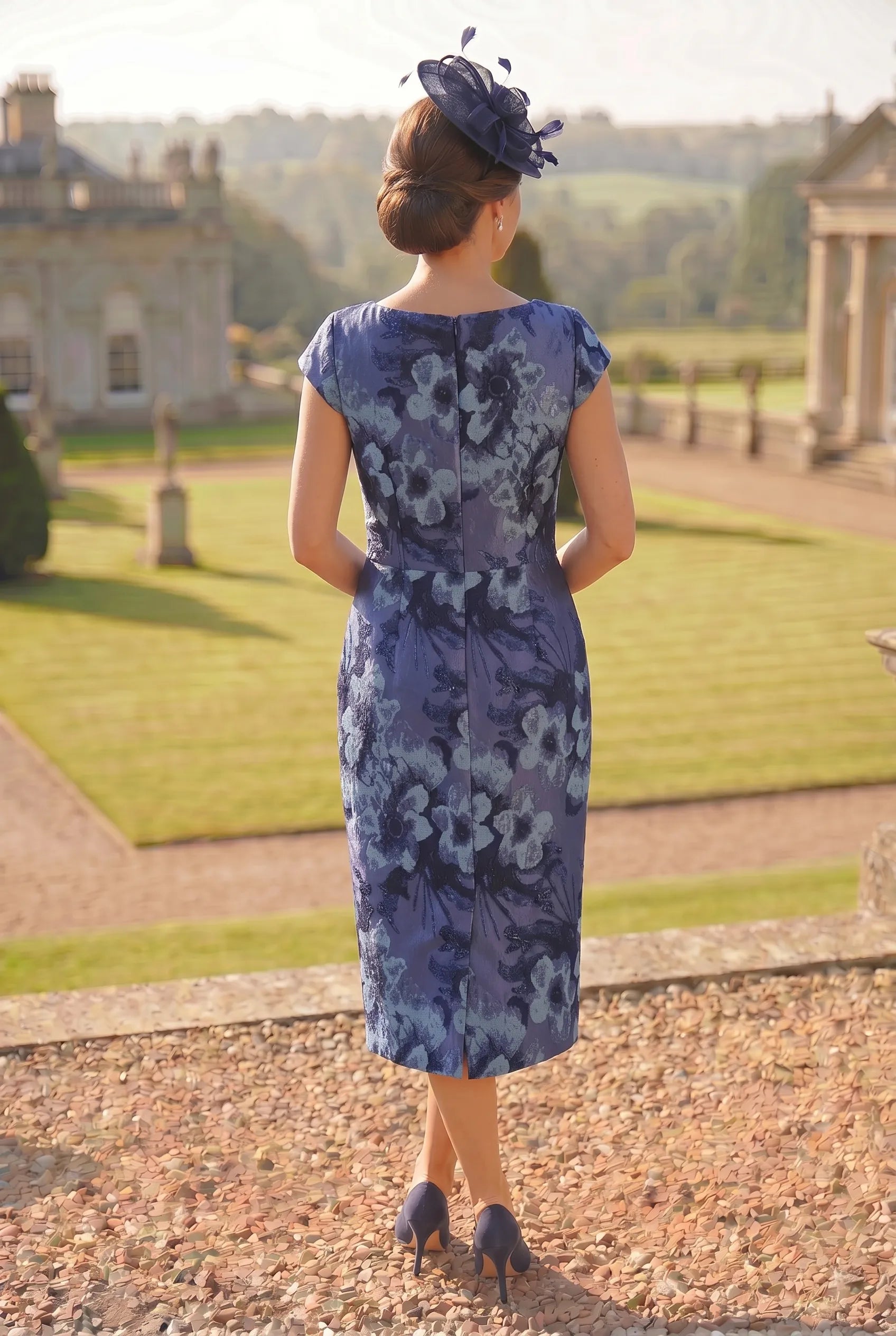 Woman in a blue floral mother of the bride dress standing in a formal garden setting